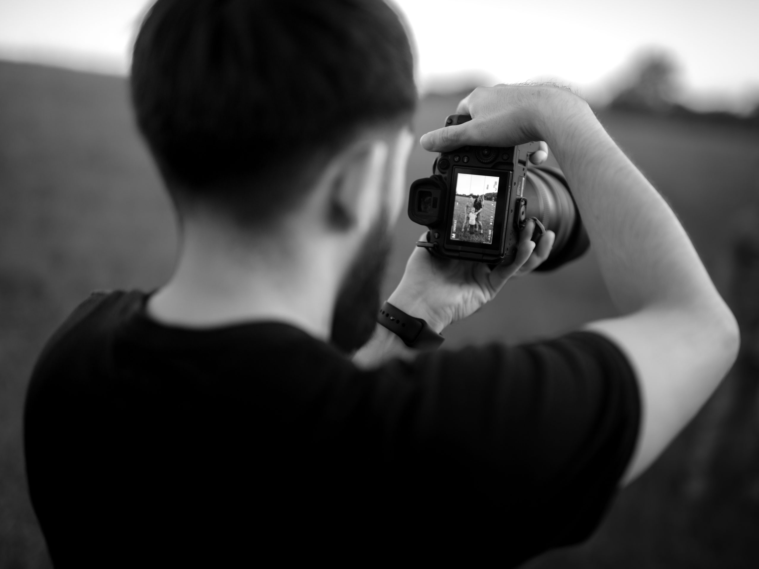 Black and white image of a photographer capturing a moment, reflecting creativity and personal ambition in the ENVISTABLACK campaign.